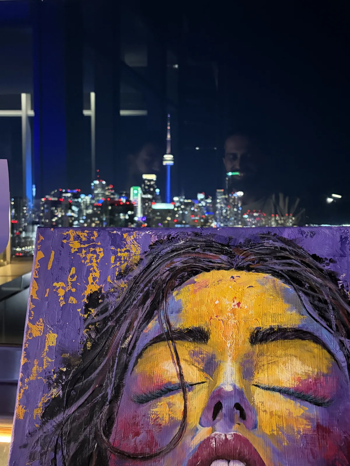 A purple and gold abstract portrait by Amit Tejpal shown against the Toronto skyline